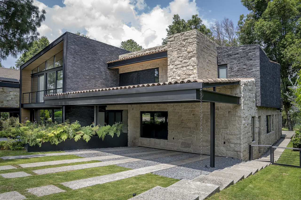 Fachada de casa contemporánea con muro de piedra vista desde el jardín, Lote 152, Rancho Avándaro, Valle de Bravo
