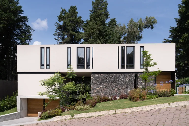 Fachada de dos niveles con acabado claro, ventanería en madera oscura y muro de piedra, Lote 267, Valle de Bravo