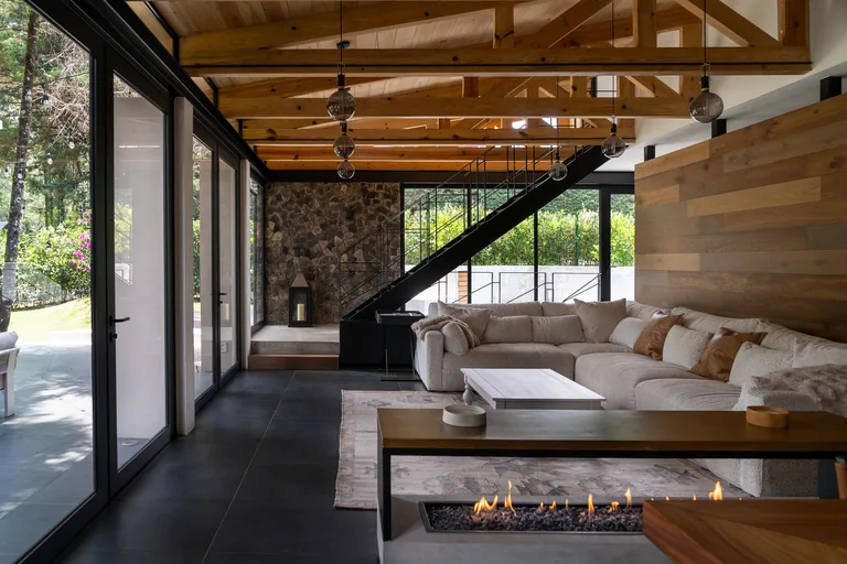 Sala amplia con techumbre de madera a dos aguas, chimenea lineal y vista al jardín, Lote 267, Valle de Bravo