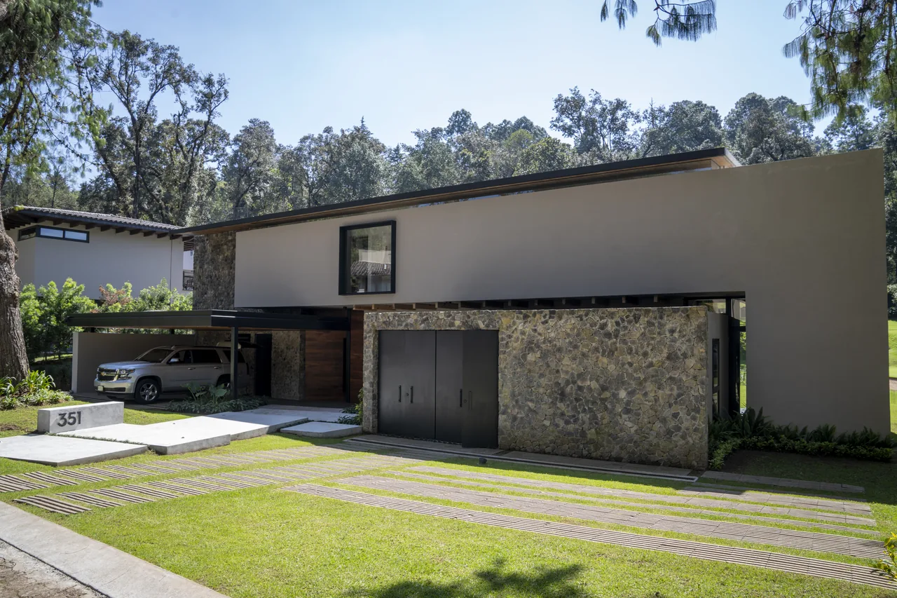 Fachada de obra entregada por el Grupo IMCI en Valle de Bravo, con muro de piedra, cochera techada